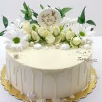 biały tort komunijny z żywymi kwiatami