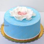 niebieski tort na chrzest z dzieckiem w płatkach kwiatka
